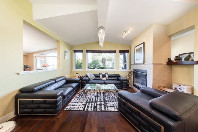 Living room with wood finished floors, vaulted ceiling, a fireplace, and baseboards | Image 8