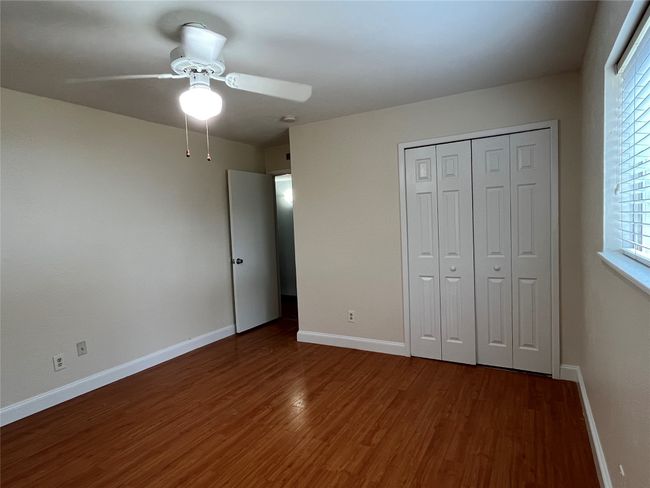 Unfurnished bedroom with wood finished floors, multiple windows, a closet, and baseboards | Image 8