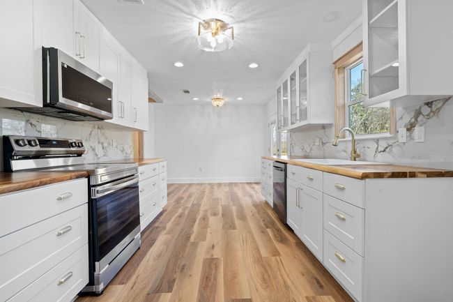 Kitchen with a sink, butcher block counters, stainless steel appliances, light wood-style flooring, and decorative backsplash | Image 24