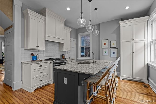 Kitchen featuring white cabinets, stainless steel range with gas cooktop, light wood finished floors, and a sink | Image 13