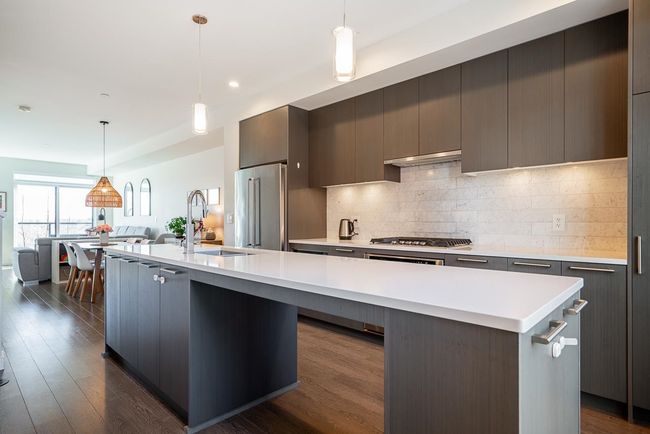 Kitchen with modern cabinets, a center island with sink, a sink, stainless steel appliances, and light countertops | Image 5