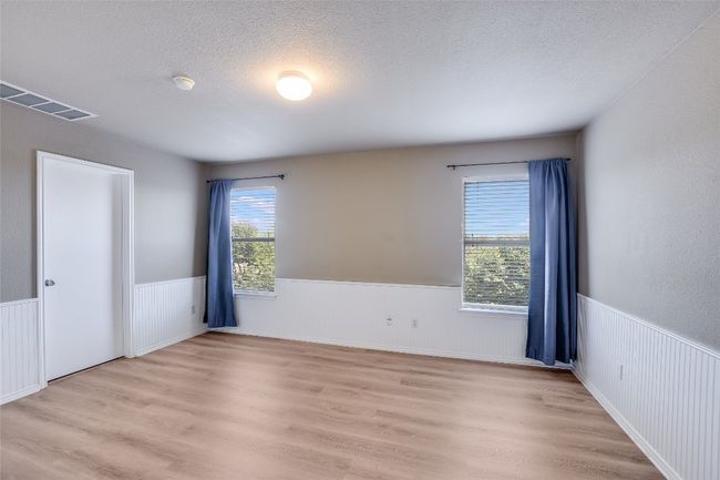 Empty room featuring a wainscoted wall, light wood-style floors, a smoke detector, and a textured ceiling | Image 11