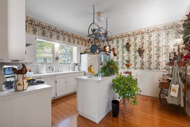 Kitchen featuring freestanding refrigerator, wallpapered walls, a wainscoted wall, light countertops, and a chandelier | Image 15
