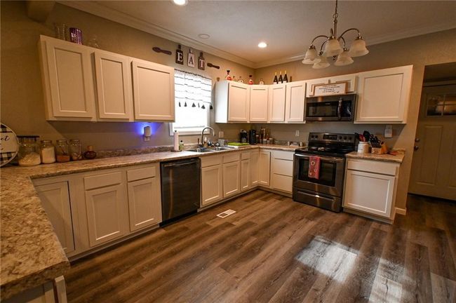 Kitchen with appliances with stainless steel finishes, a sink, a chandelier, ornamental molding, and recessed lighting | Image 14
