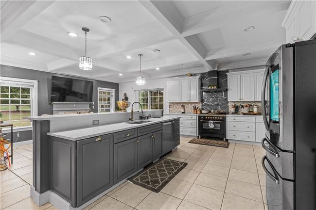 Kitchen featuring stainless steel appliances, a sink, white cabinets, coffered ceiling, and backsplash | Image 8