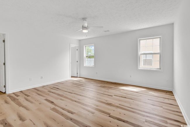 Empty room featuring ceiling fan, a textured ceiling, visible vents, light wood-type flooring, and baseboards | Image 13
