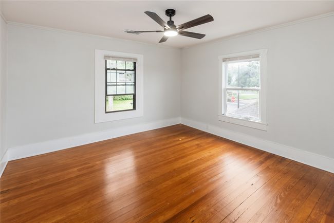 Empty room with wood-type flooring, ornamental molding, baseboards, and ceiling fan | Image 15