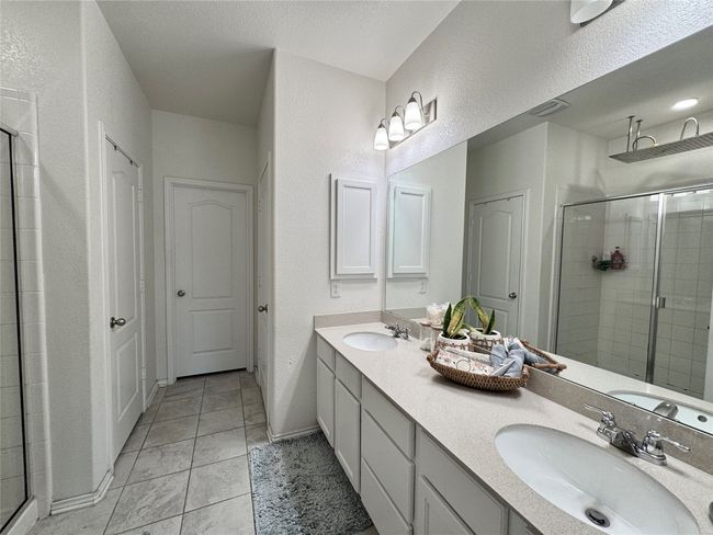 Full bathroom with a shower stall, double vanity, a textured wall, and tile patterned floors | Image 19