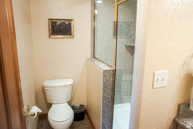 Full bath featuring a textured wall, toilet, baseboards, tile patterned floors, and a stall shower | Image 20