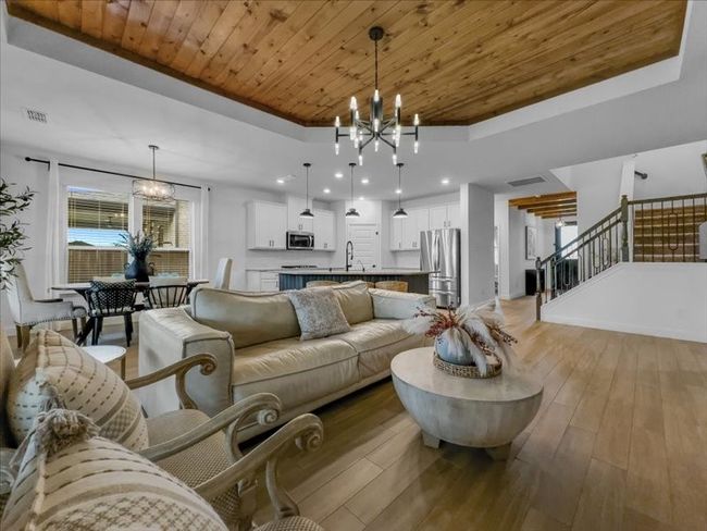 Living area with a chandelier, wooden ceiling, a raised ceiling, stairs, and light wood-style flooring | Image 15