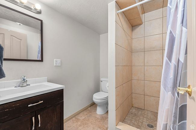 Full bath featuring vanity, toilet, tiled shower, and baseboards | Image 22