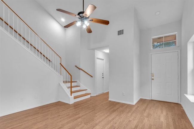 Foyer entrance featuring a high ceiling, light wood-style floors, ceiling fan, and stairs | Image 6