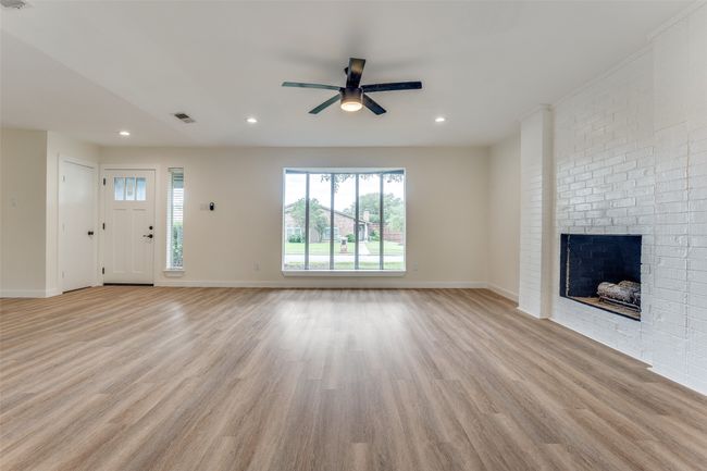 Unfurnished living room featuring a ceiling fan, light wood finished floors, a brick fireplace, baseboards, and recessed lighting | Image 6