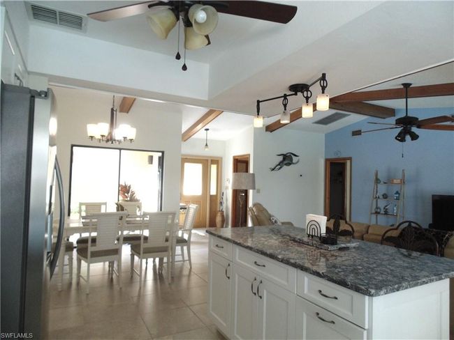 Kitchen with open floor plan, ceiling fan with notable chandelier, visible vents, and freestanding refrigerator | Image 9