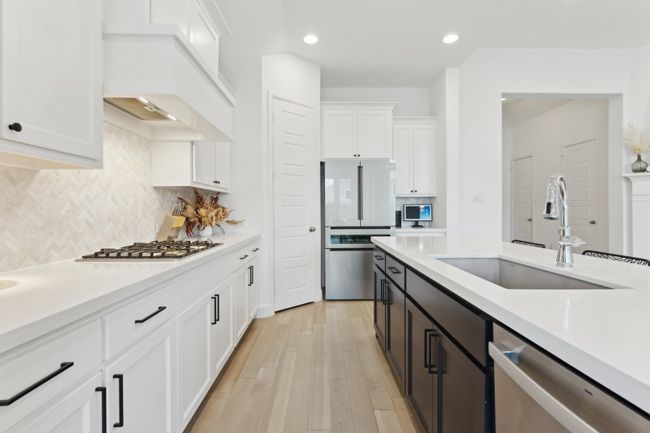Kitchen featuring stainless steel appliances, a sink, white cabinets, light countertops, and recessed lighting | Image 9