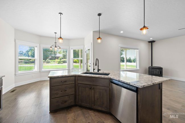 Kitchen featuring stainless steel dishwasher, a wood stove, dark wood finished floors, dark brown cabinets, and recessed lighting | Image 6