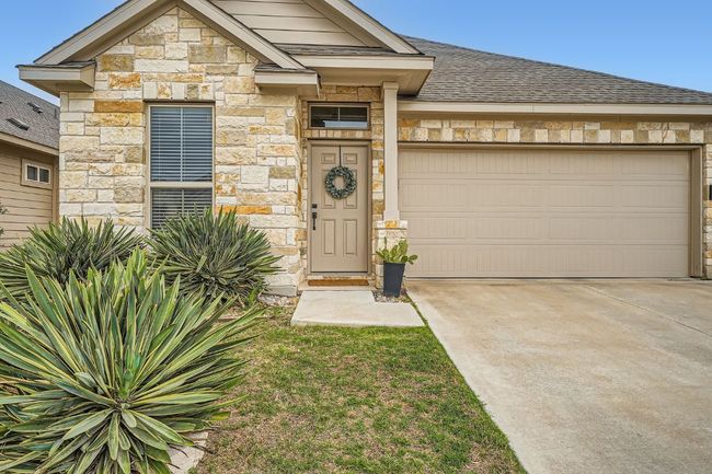 View of front facade featuring a shingled roof, driveway, a garage, and stone siding | Image 27