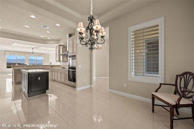 Kitchen with visible vents, an inviting chandelier, a tray ceiling, recessed lighting, and a kitchen island | Image 12