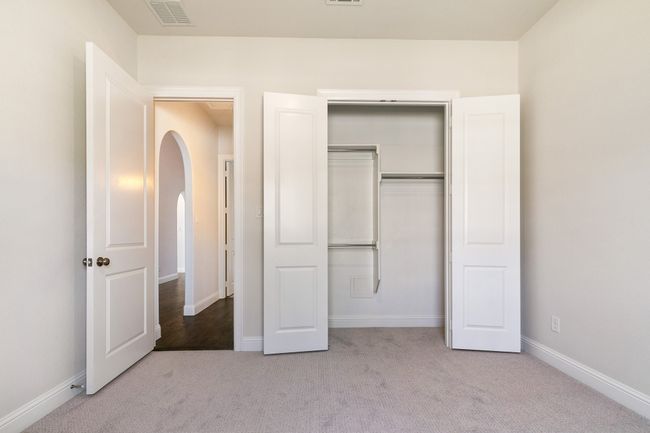 Unfurnished bedroom with carpet floors, arched walkways, baseboards, and visible vents | Image 6