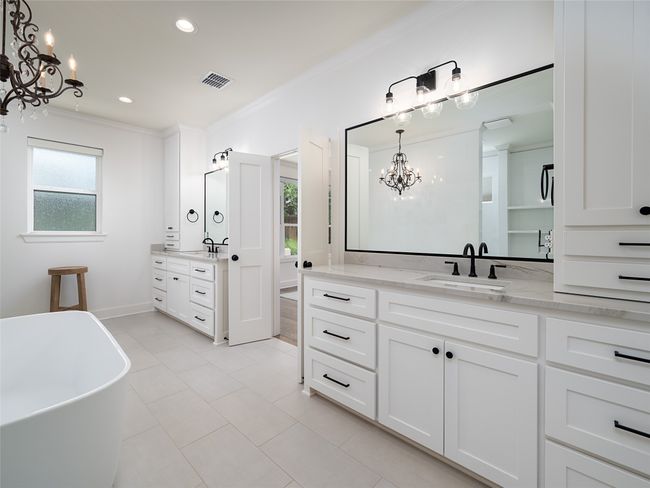 Full bathroom featuring a chandelier, two vanities, healthy amount of natural light, ornamental molding, and a freestanding bath | Image 19