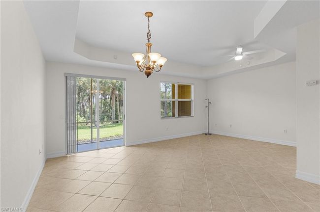 Empty room featuring a tray ceiling, a chandelier, ceiling fan, and light tile patterned flooring | Image 10