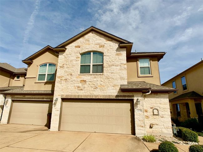 Townhome / multi-family property with stone siding, a garage, concrete driveway, and stucco siding | Image 14