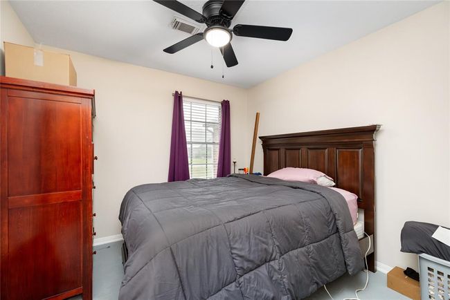 A secondary bedroom with ceiling fan and natural light offers a simple, adaptable space for guests, home office use, or daily living. | Image 15