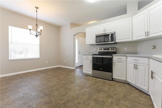 Kitchen featuring stainless steel appliances, arched walkways, a chandelier, and white cabinetry | Image 14