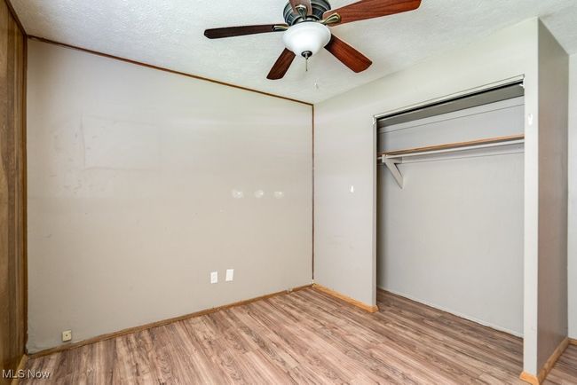 Unfurnished bedroom with light wood-style flooring, a closet, a textured ceiling, baseboards, and ceiling fan | Image 29