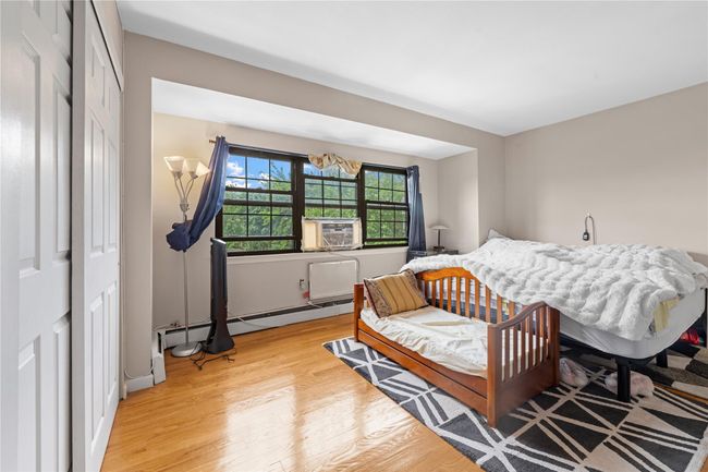 Bedroom with light wood-style flooring, a closet, a baseboard radiator, cooling unit, and a chandelier | Image 7