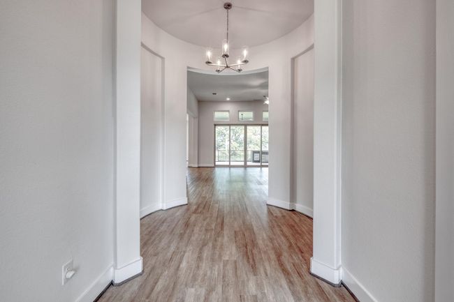Corridor with a chandelier and light wood-style floors | Image 5