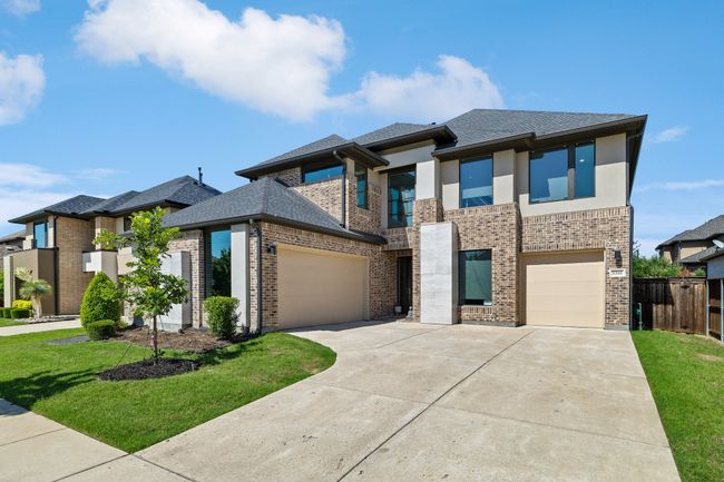 View of front facade with brick siding, driveway, a shingled roof, and stucco siding | Image 40