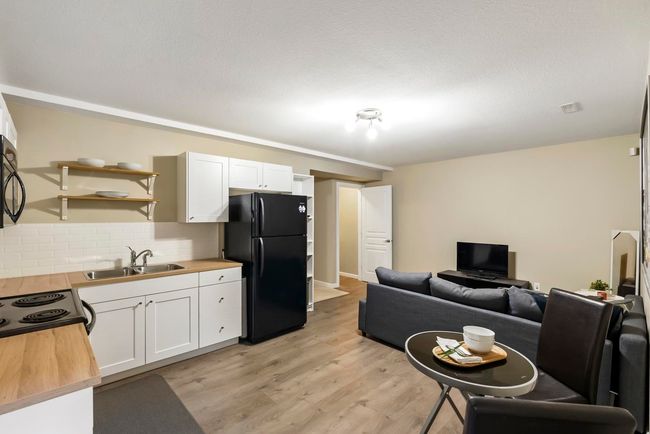 Kitchen with open shelves, a sink, black appliances, wood counters, and white cabinetry | Image 27