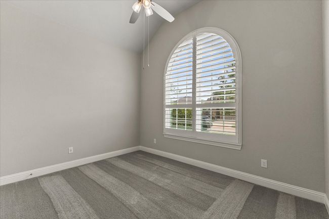 Spare room featuring natural light, carpet, a ceiling fan, lofted ceiling & plantation shutters | Image 5