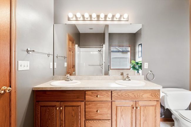 Double vanity with ample counter space and storage, accented by a large mirror and warm oak cabinetry. | Image 29