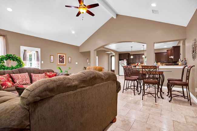 Spacious living room with high vaulted ceiling, ceiling fan, arched walkways. | Image 12