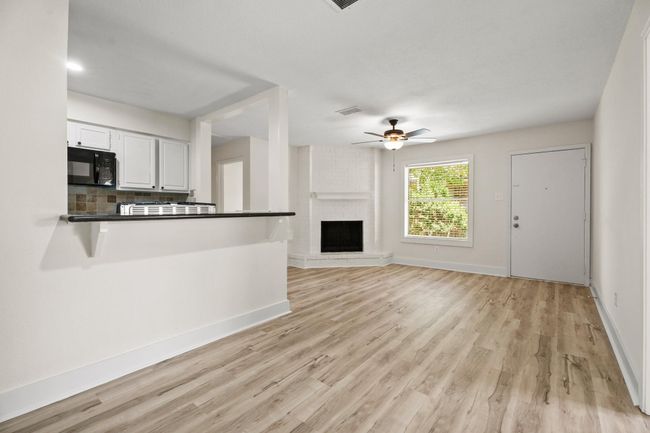 Your spacious living room is open to the kitchen and dining room. The corner gas fireplace provides both warmth and a beautiful focal point. The entire home features brand new luxury vinyl plank flooring and new interior paint. | Image 4