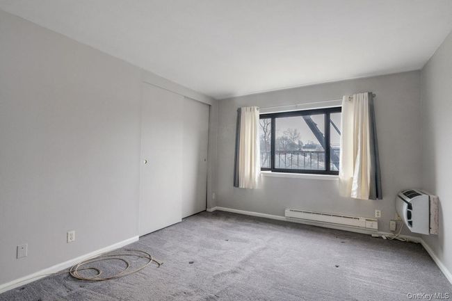 Carpeted spare room with baseboard heating, a wall unit AC, and baseboards | Image 15