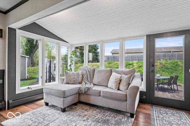 sunroom / solarium with a baseboard heating unit, lofted ceiling, wood finished floors, a deck, and ornamental molding | Image 12