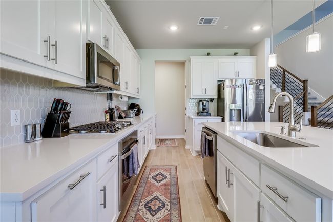 Kitchen with appliances with stainless steel finishes, a sink, light countertops, tasteful backsplash, and light wood finished floors | Image 13