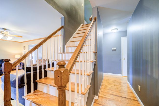 Staircase featuring wood finished floors, a ceiling fan, and baseboards | Image 4
