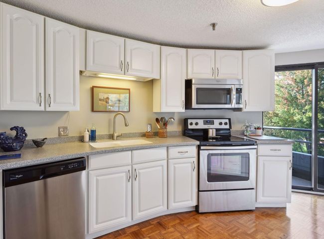 Thoughtfully updated kitchen with Corian countertops, stainless steel appliances, and newer cabinetry. | Image 9