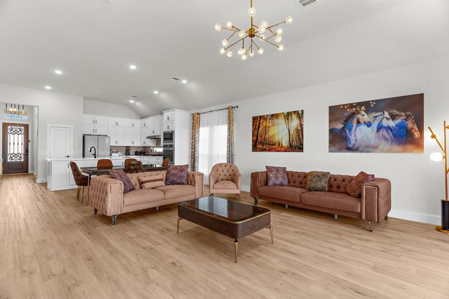 Living room with a chandelier, vaulted ceiling, light wood-type flooring, recessed lighting, and baseboards | Image 16