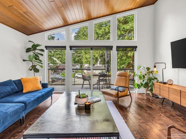 Spacious open concept living Room with vaulted warm wood ceiling, full height west facing (new) windows flooding the room with natural light, and a cozy gas fireplace as a central focal point in the 'Great Room'. | Image 10