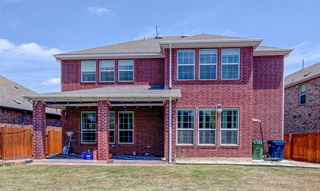 Rear view of house featuring a patio area, a lawn, a shingled roof, a fenced backyard, and brick siding | Image 30