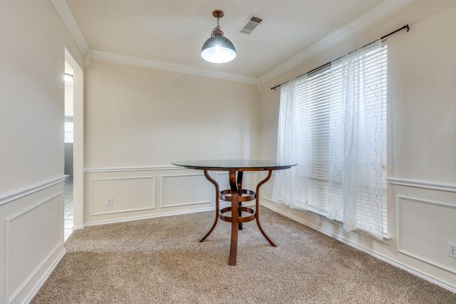 Unfurnished dining area featuring a wainscoted wall, carpet floors, a decorative wall, visible vents, and ornamental molding | Image 6