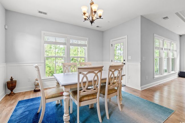 Dining space featuring wainscoting, healthy amount of natural light, light wood-type flooring, and a chandelier | Image 10