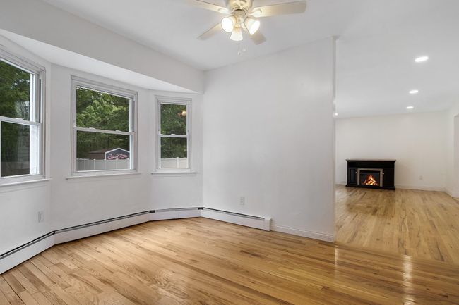 Unfurnished living room with light wood-style floors, a ceiling fan, a warm lit fireplace, baseboards, and recessed lighting | Image 11