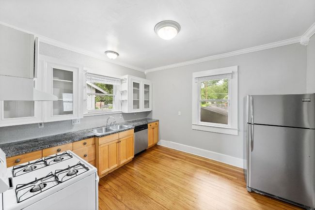 Kitchen featuring stainless steel appliances, a sink, crown molding, light wood-type flooring, and baseboards | Image 7