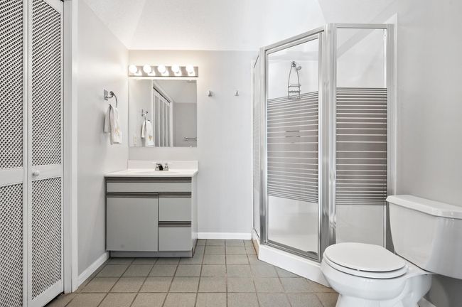 The three quarter bathroom is adjacent to the spa on the lower level. It offers an impressive tray ceiling, a convenient walk-in shower, a single vanity, and a large closet for storage. | Image 33